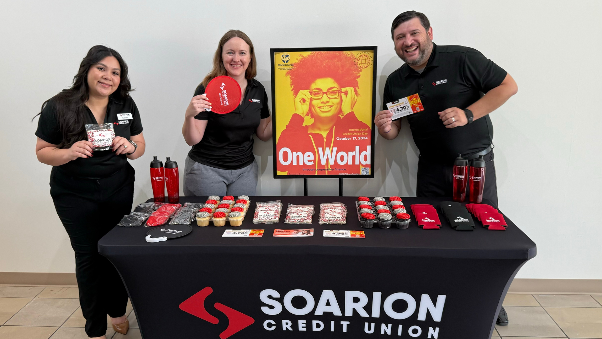 Group of soarion employees standing at a promo table for International Credit Union Day
