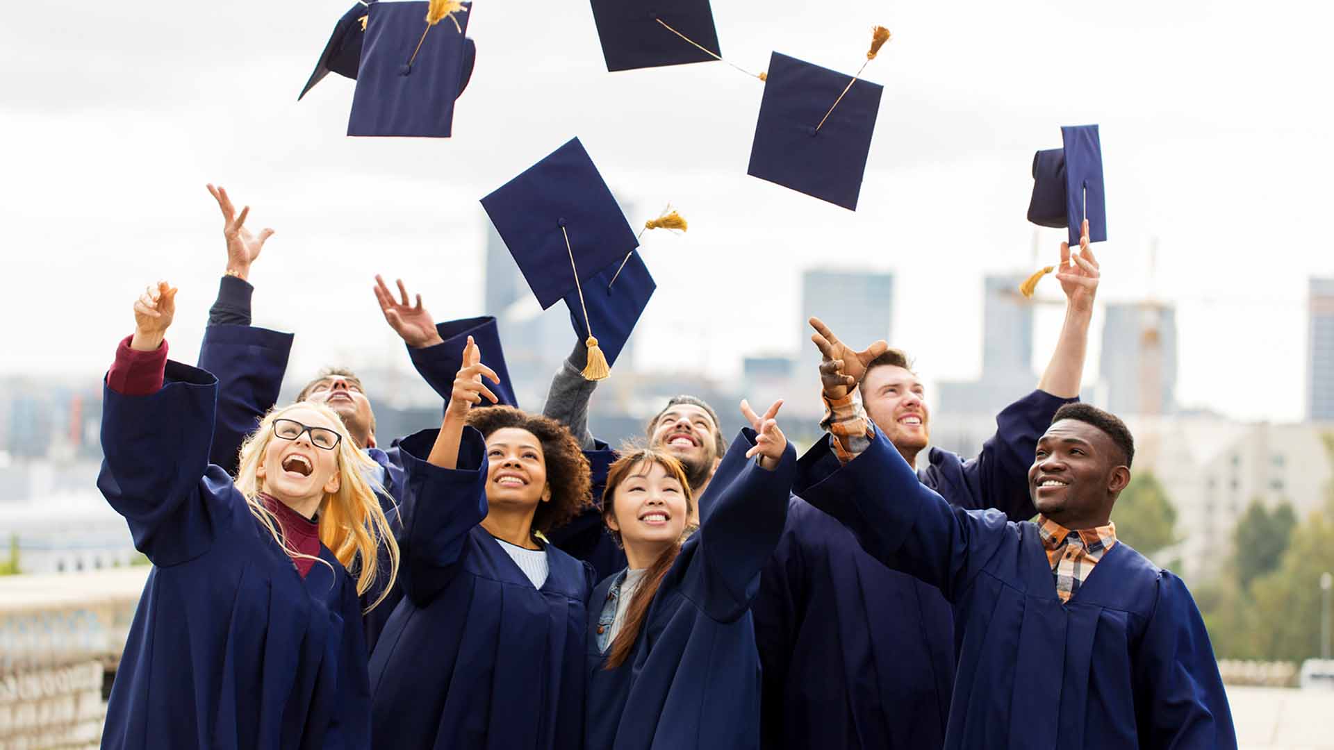Group of happy graduates throwing their cap into the air
