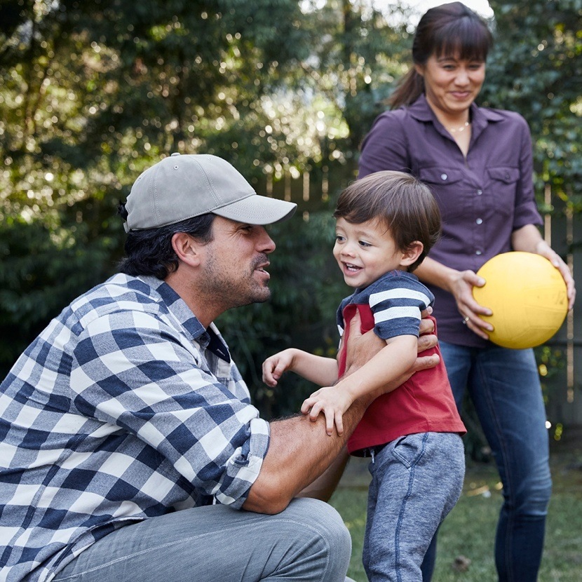 Happy couple and son outside with ball